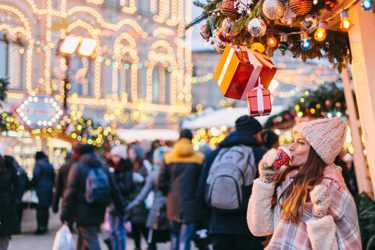 Woman standing drinking coffee while crowds of shoppers walk by