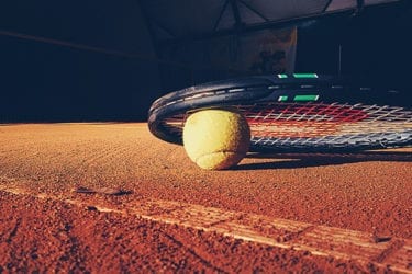 Tennis racket and ball on dirt court