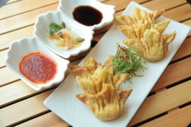 Wontons with dipping sauce on wooden table
