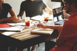 Staff sitting around a table with notebooks and a laptop