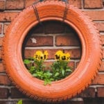 Orange tire hung on brick wall as planter