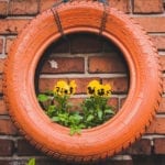 Orange tire hung on brick wall as planter