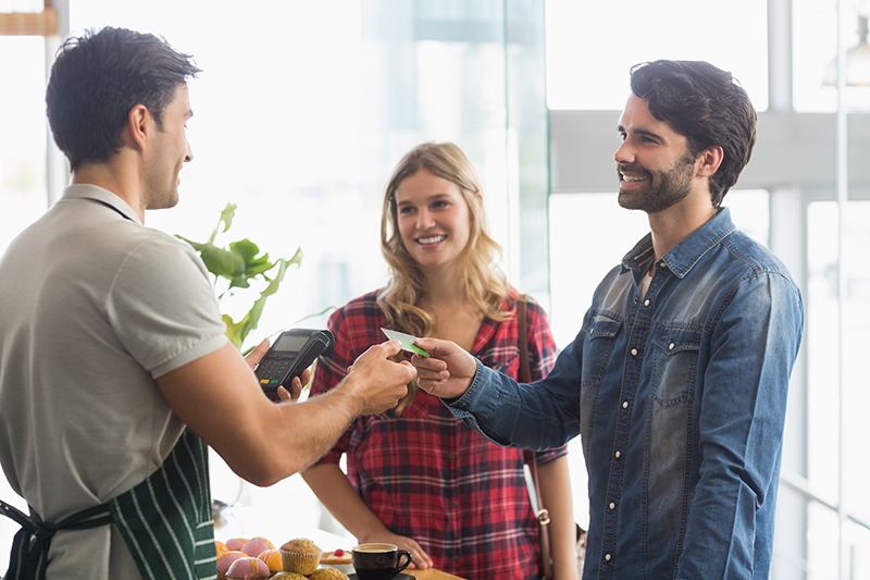 Male and female customers paying a merchants with a credit card