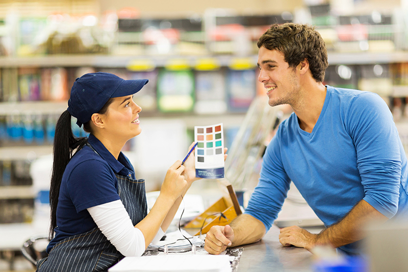 Male customer talking to paint specialist woman in a store