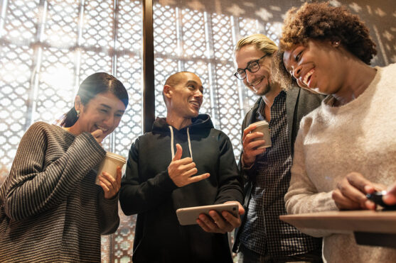 Four people gathered around looking at a guys cell phone