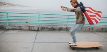 Man riding longboard wearing an American flag