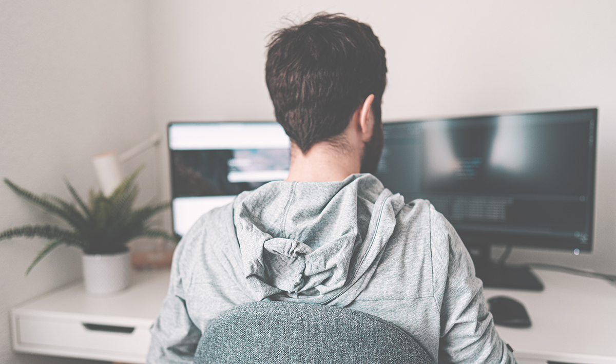 Back of man working at computer at home