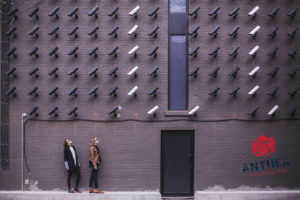 Security cameras on a wall staring at two women on the street