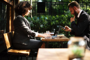 Woman and man sitting at a table with a laptop and a phone