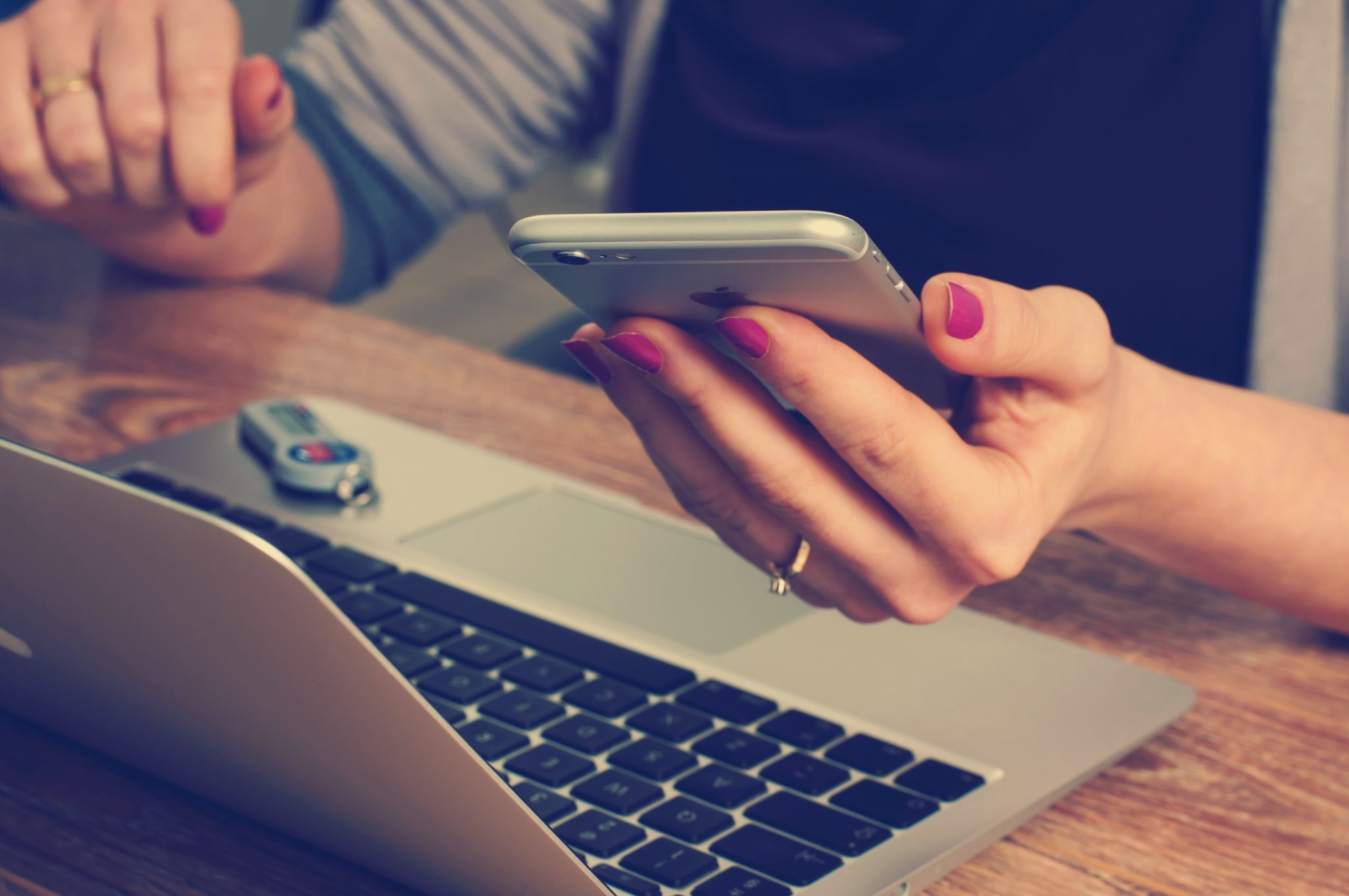 Woman holding mobile phone ordering something online from a computer