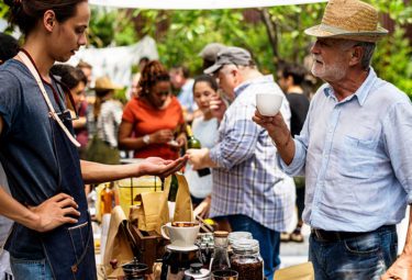 Local coffee roaster talking with a customer at an outdoor market