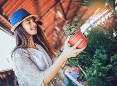 Woman in a hat holding a plant in a garden center