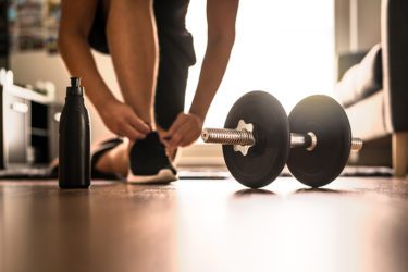 Woman tying her shoe at her home gym