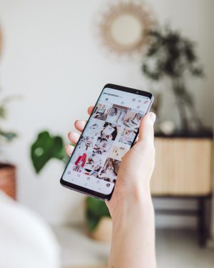 Woman's hand holding a phone looking at instagram