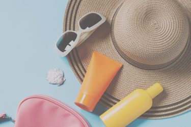 Sunglasses, Hat, Sunscreen, Clutch all on a table