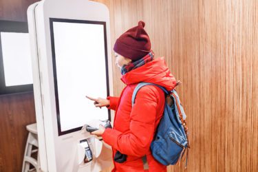 Woman in a red jacket using a kiosk