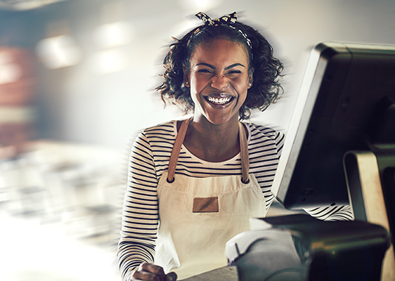 Laughing young woman, working retail, standing next to a POS terminal