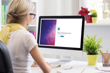 Woman sitting at desk looking at RCS Portal login screen on her computer