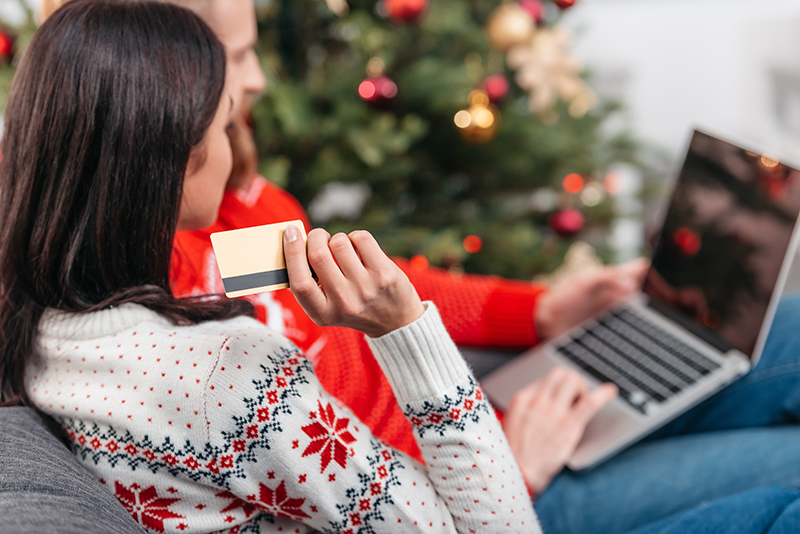 Cropped image of young couple shopping online with credit card and laptop at Christmas