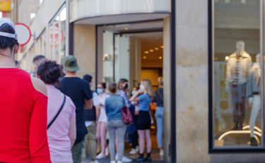 People standing in a long line outside of a retail shop