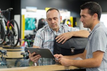 Two men looking at a tablet in a bike shop.