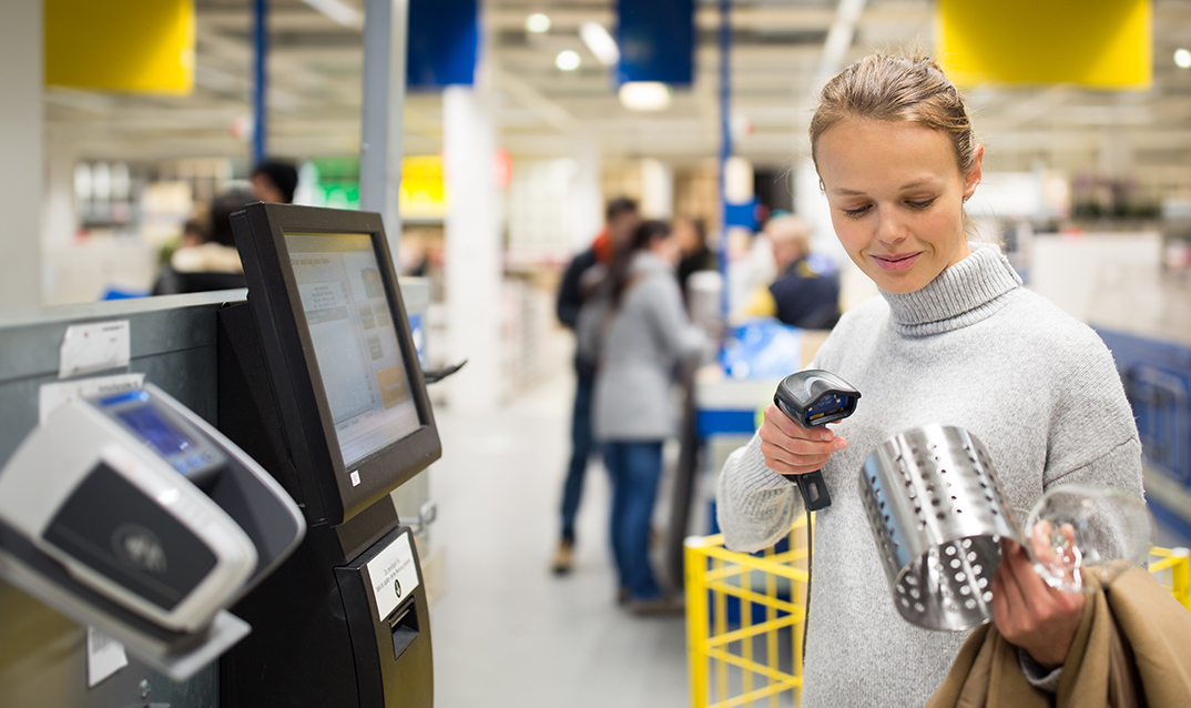 Young woman using self service checkout in a store.