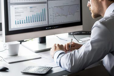 Man monitoring data on two computer monitors