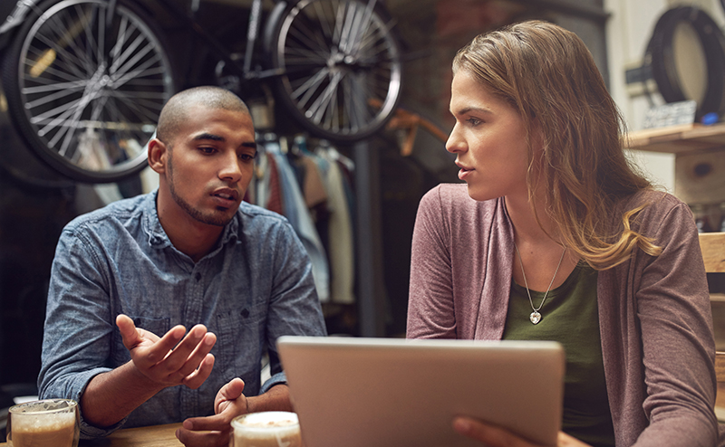 A young man and woman using a digital tablet together at a bike shop