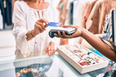 Woman taps her credit card to pay a retailer.