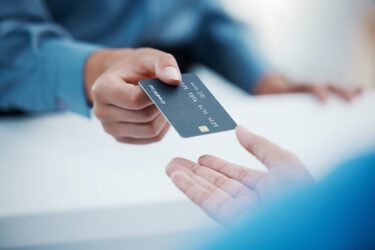 Person handing a retailer a credit card for payment.