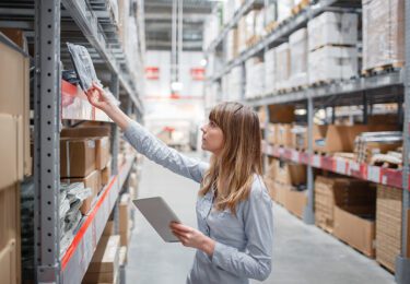 Women checking inventory in large warehouse.