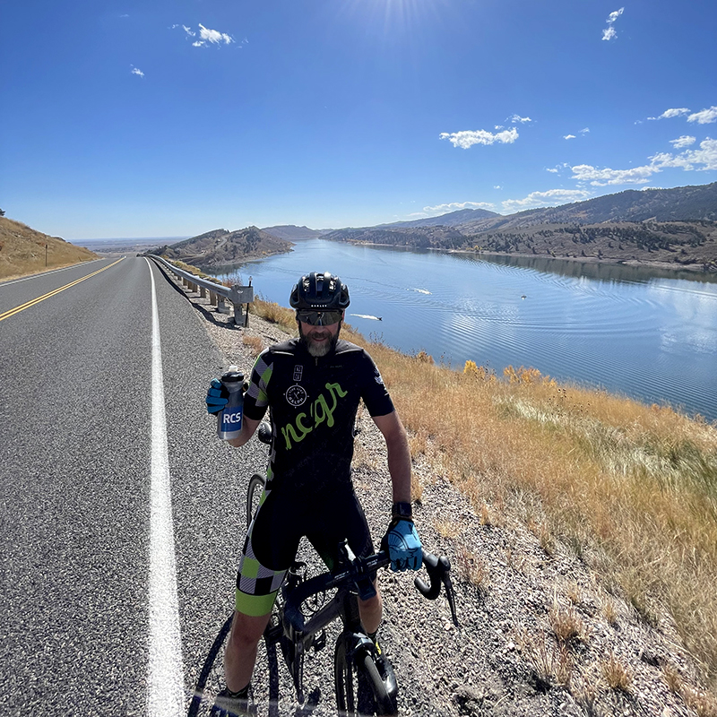 Richard standing over his bike with an RCS water bottle in his hand at Horsetooth Reservoir in Colorado.