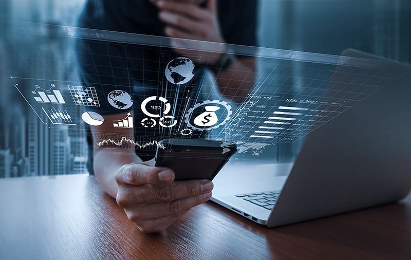 Businessman using smartphone to look at his accounting information with a computer next to him.