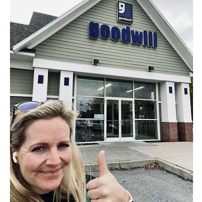 Jill standing in front of her local Goodwill store (GW Northern New England) giving a thumbs up.