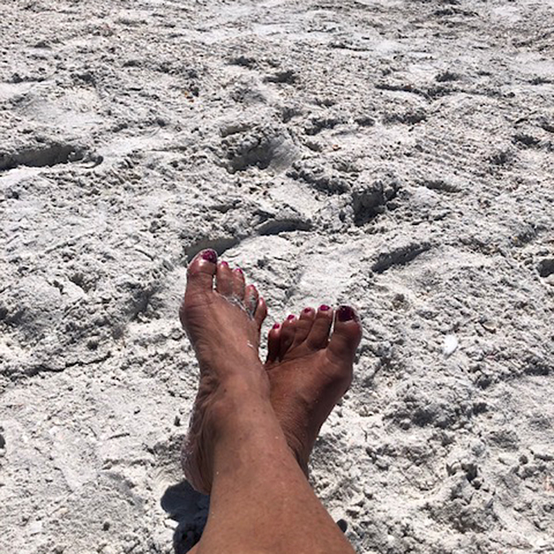 Karen's feet in the sand at the beach.