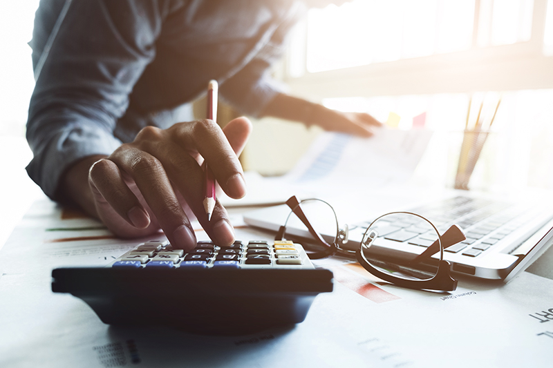 Close up of accountant hand holding pen working on calculator to calculate business data.