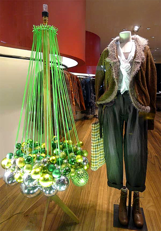 Hanging ornaments made to look like a tree next to a mannequin displaying retail clothing.