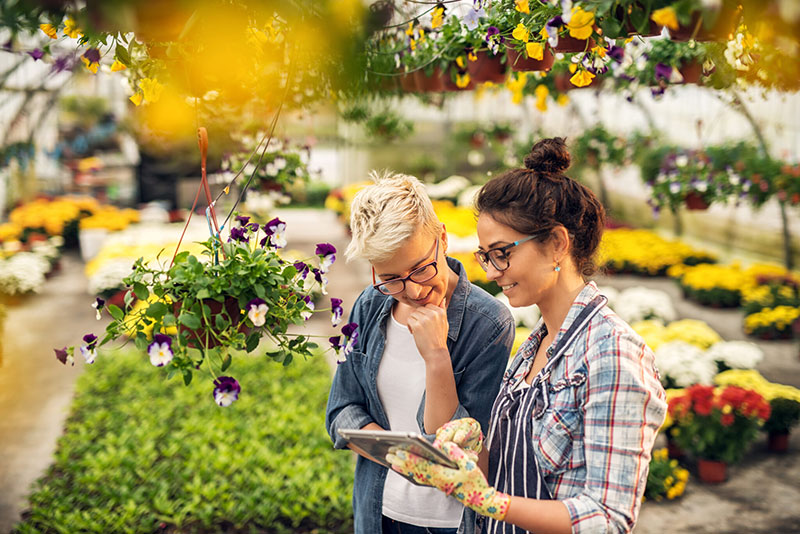 Two women looking at a tablet in a garden center