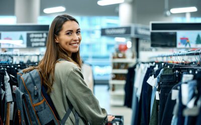 Woman wearing a backpack shopping in a clothing store, looking at the camera.