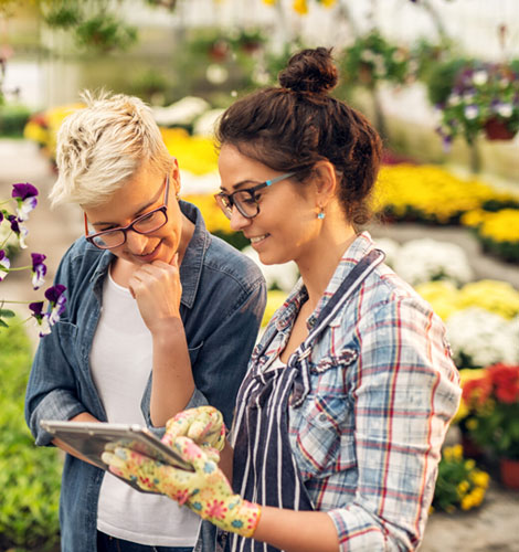 Two women reviewing a tablet at a garden center