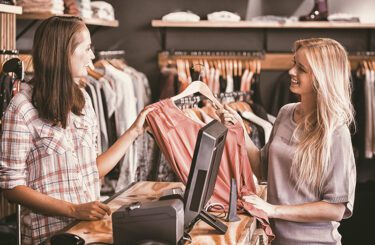 A woman buying a shirt at the checkout counter of a clothing store.