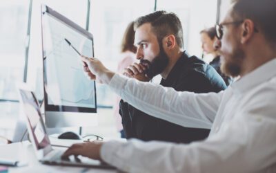 Two guys looking at a computer screen in an office.