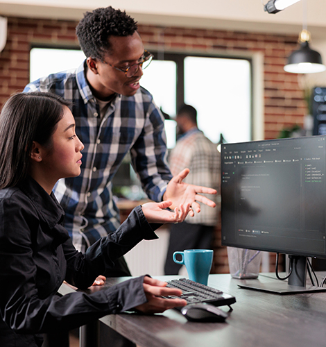 Man and woman looking at data on a computer monitor talking about data security.