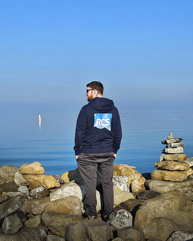 Dustin at a lake wearing an RCS sweatshirt.