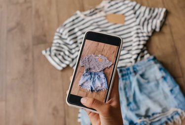 Person taking a picture of secondhand clothing with a phone to post online.