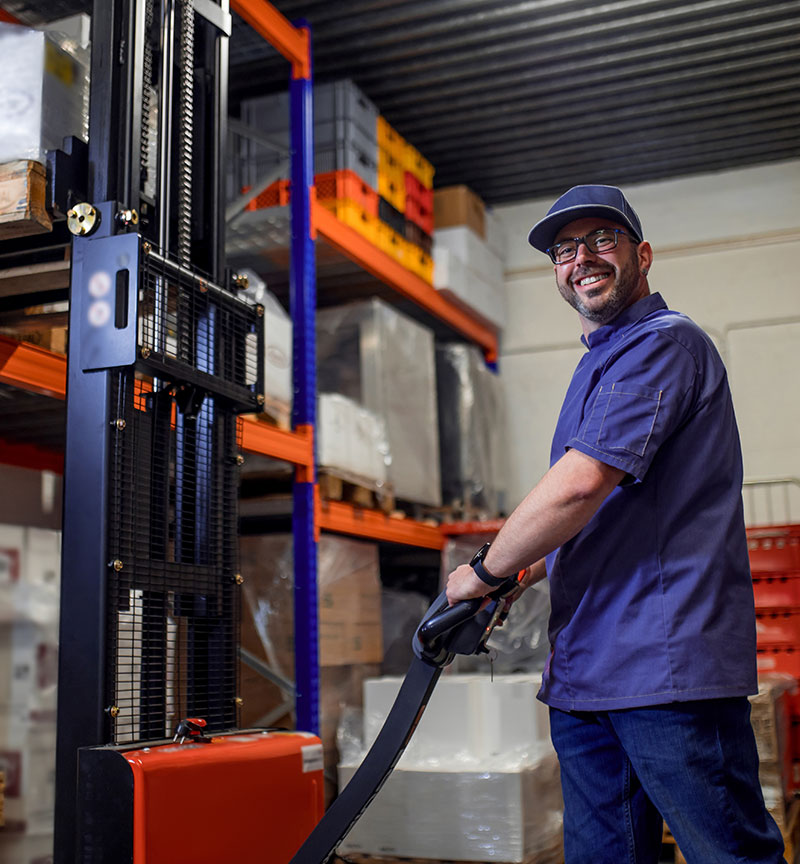Man using a forklift in a warehouse for a wholesale retailer.